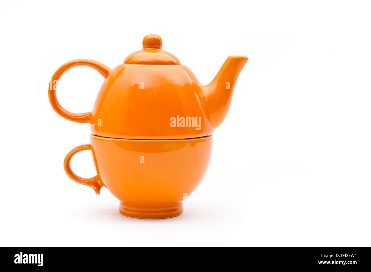 Teaset. Single orange Teekanne und Tasse auf einem weißen Hintergrund. Teekanne konzipiert auf der Schale sitzen. Stockfoto