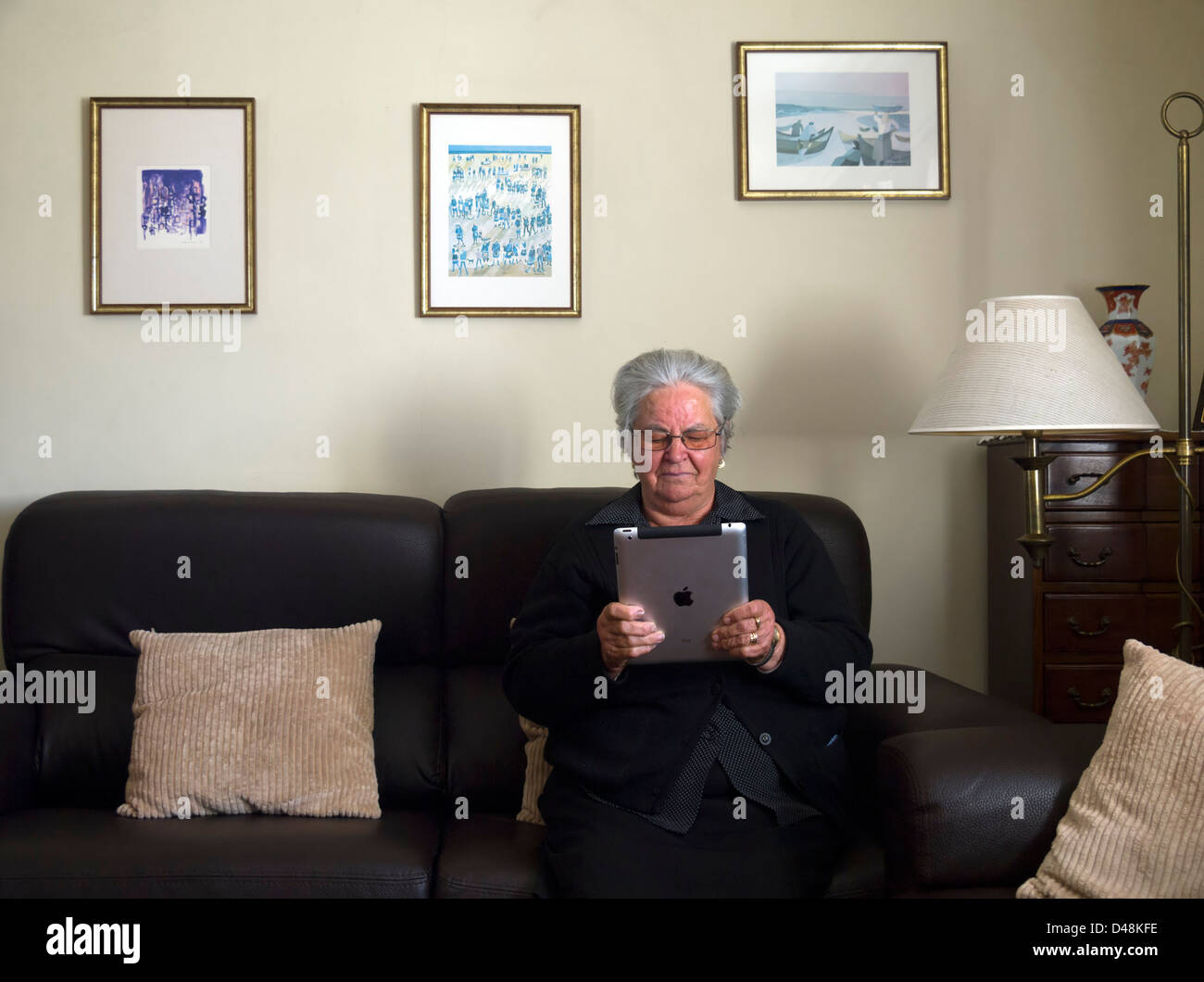 Reife Frau mit dem iPad zu Hause sitzen auf dem sofa Stockfoto