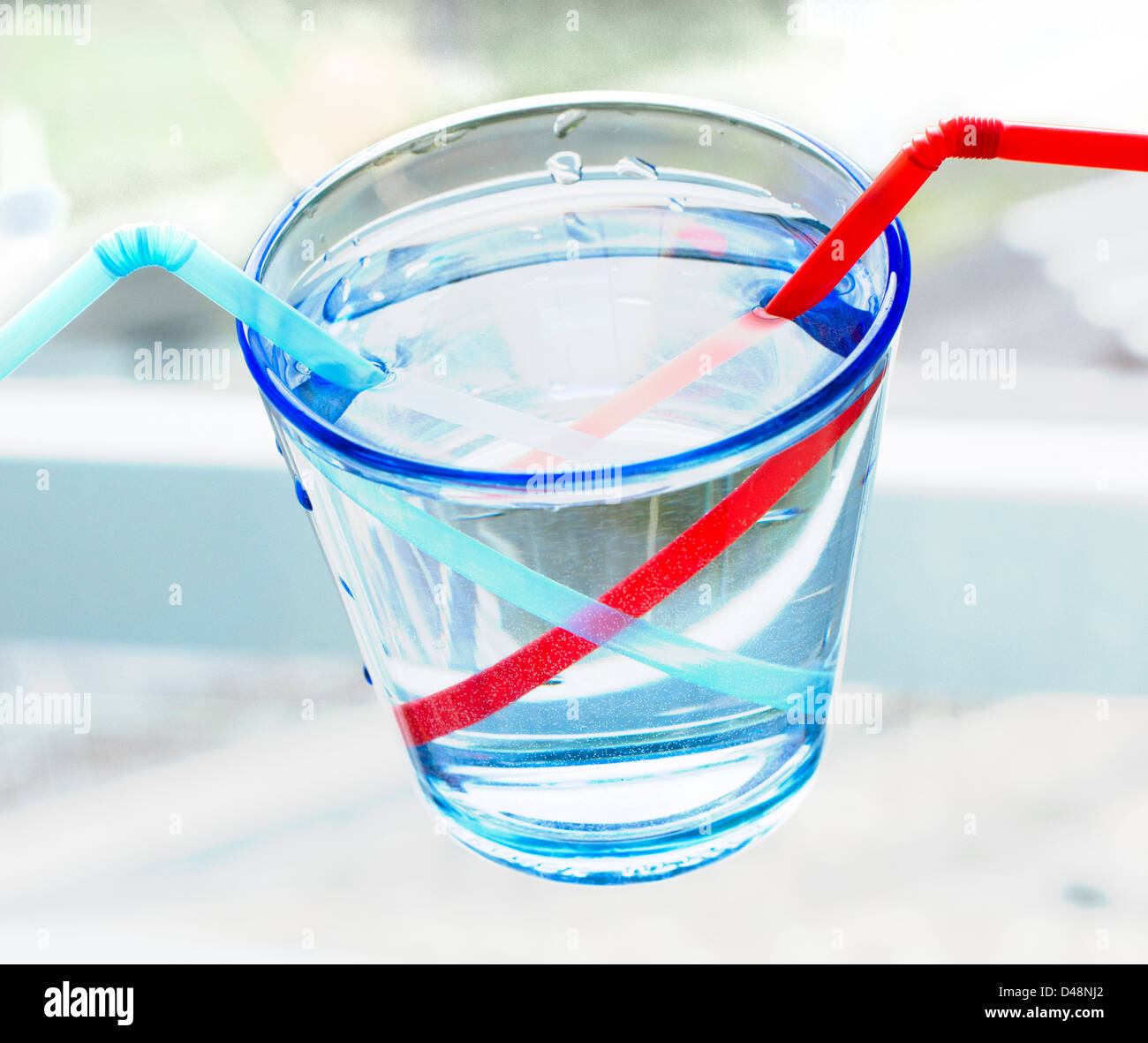 Glas mit zwei Strohhalmen zeigt Lichtbrechung im Wasser Stockfoto