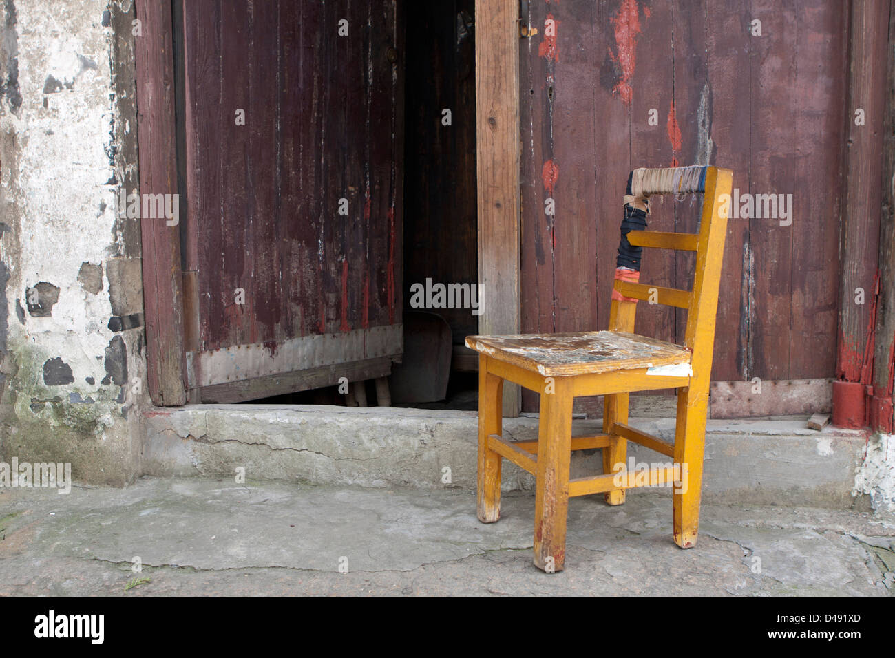 Eine gut verwendet Holzstuhl außerhalb einer Werkstatt in einem chinesischen Fischerdorf Stockfoto