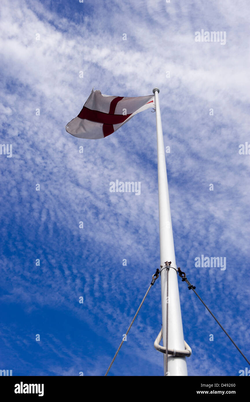 Englische Flagge von St. George an Spitze der Fahnenstange gegen blauen Himmel fliegen Stockfoto