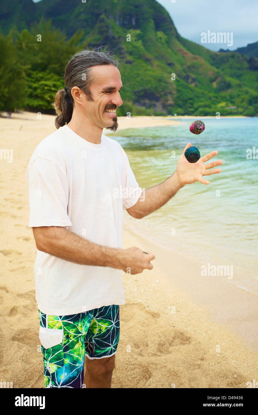 Ein Mann jongliert mit Hackey Säcke stehen am Strand am Rand des Wassers; Hawaii Vereinigte Staaten von Amerika Stockfoto