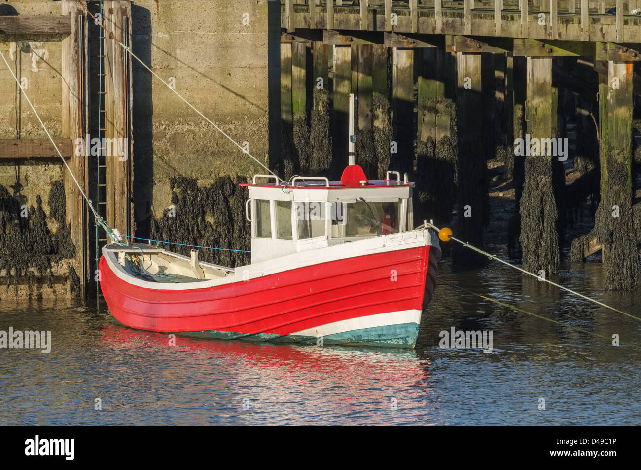 Kleine rote und weiße Fischerboot vor Anker, piers Stockfoto