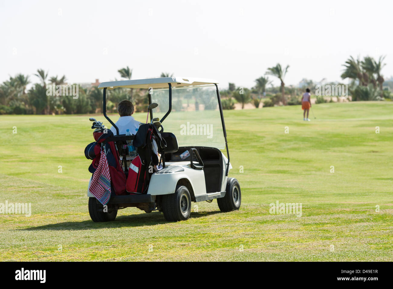 Elektro-Golf-Buggy getrieben auf dem Fairway mit Golfer in der Ferne Stockfoto