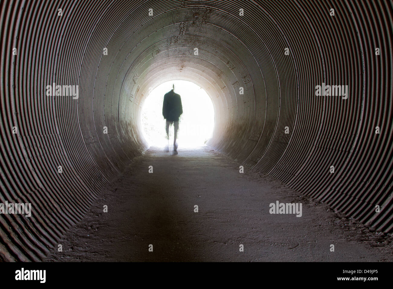 Ein einzelner Mann zu Fuß durch einen Tunnel in das Licht Stockfoto