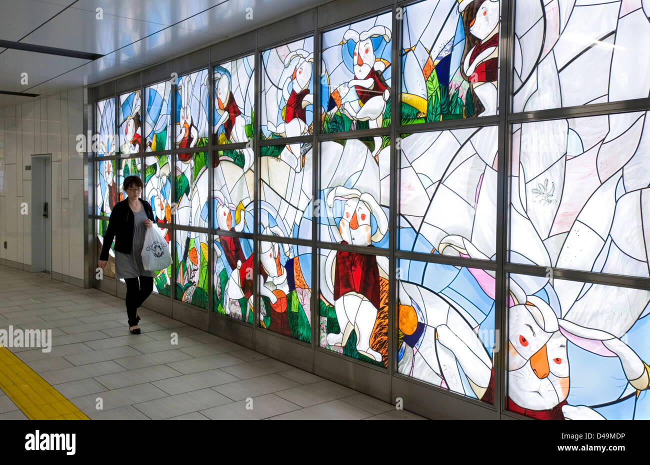 Eine beleuchtete Kirchenfenster Kunst Wand erhellt einen unterirdischen Gang in die Metro u-Bahn von Tokio. Stockfoto