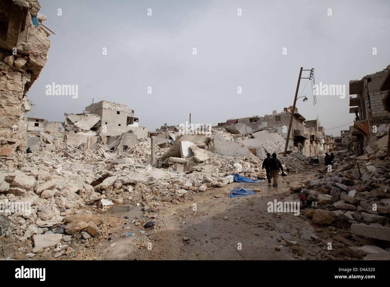 Die Menschen gehen durch beschädigte Gebäude nach eine Oberfläche zu Oberfläche Rakete Tariq Al-Bab-Abschnitt von Aleppo getroffen. Stockfoto