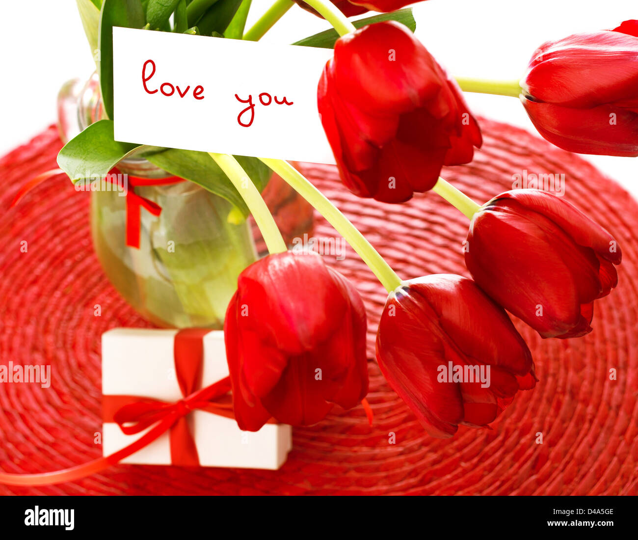 Foto von schöne rote Tulpe Blumen Bukett und romantische Postkarte drin mit kleinen weißen Geschenkbox auf dem Tisch, Frühling Stockfoto