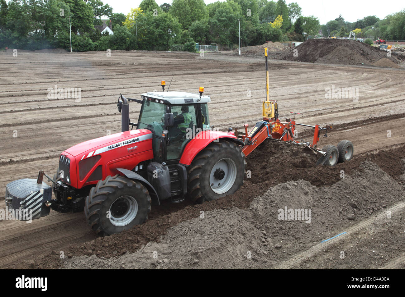 Ein Traktor schleppt geführte eine Sortiermaschine mit einem Laser Level-System zum Erstellen von ebenem Boden für einen neuen Sportplatz in Woking Stockfoto