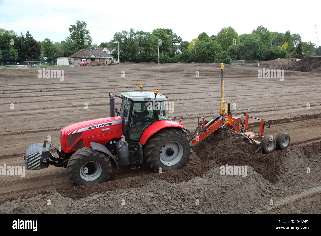 Ein Traktor schleppt geführte eine Sortiermaschine mit einem Laser Level-System zum Erstellen von ebenem Boden für einen neuen Sportplatz in Woking Stockfoto