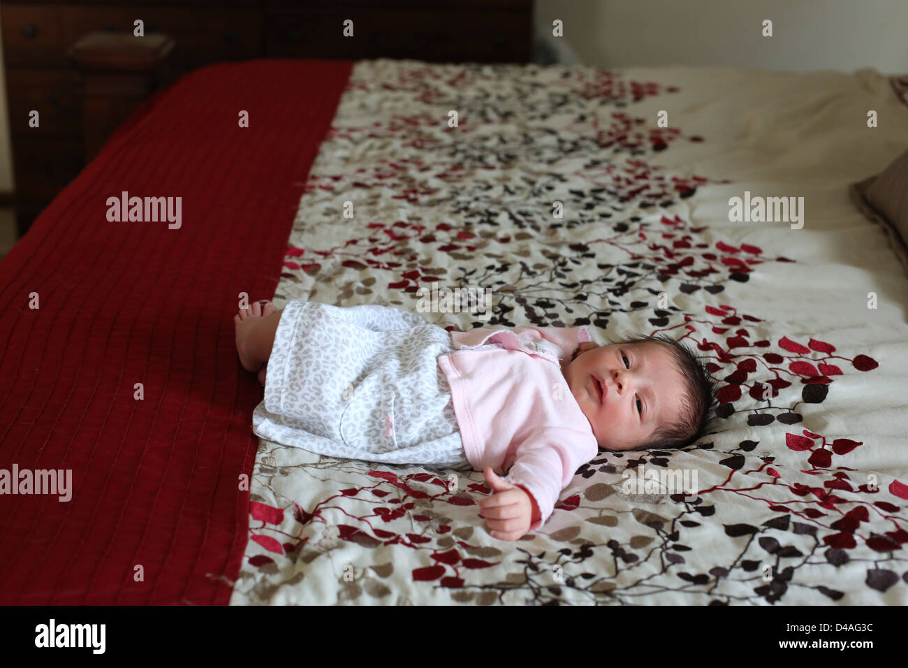 Ein kleines neugeborenes Baby liegend auf einem großen Bett. Stockfoto