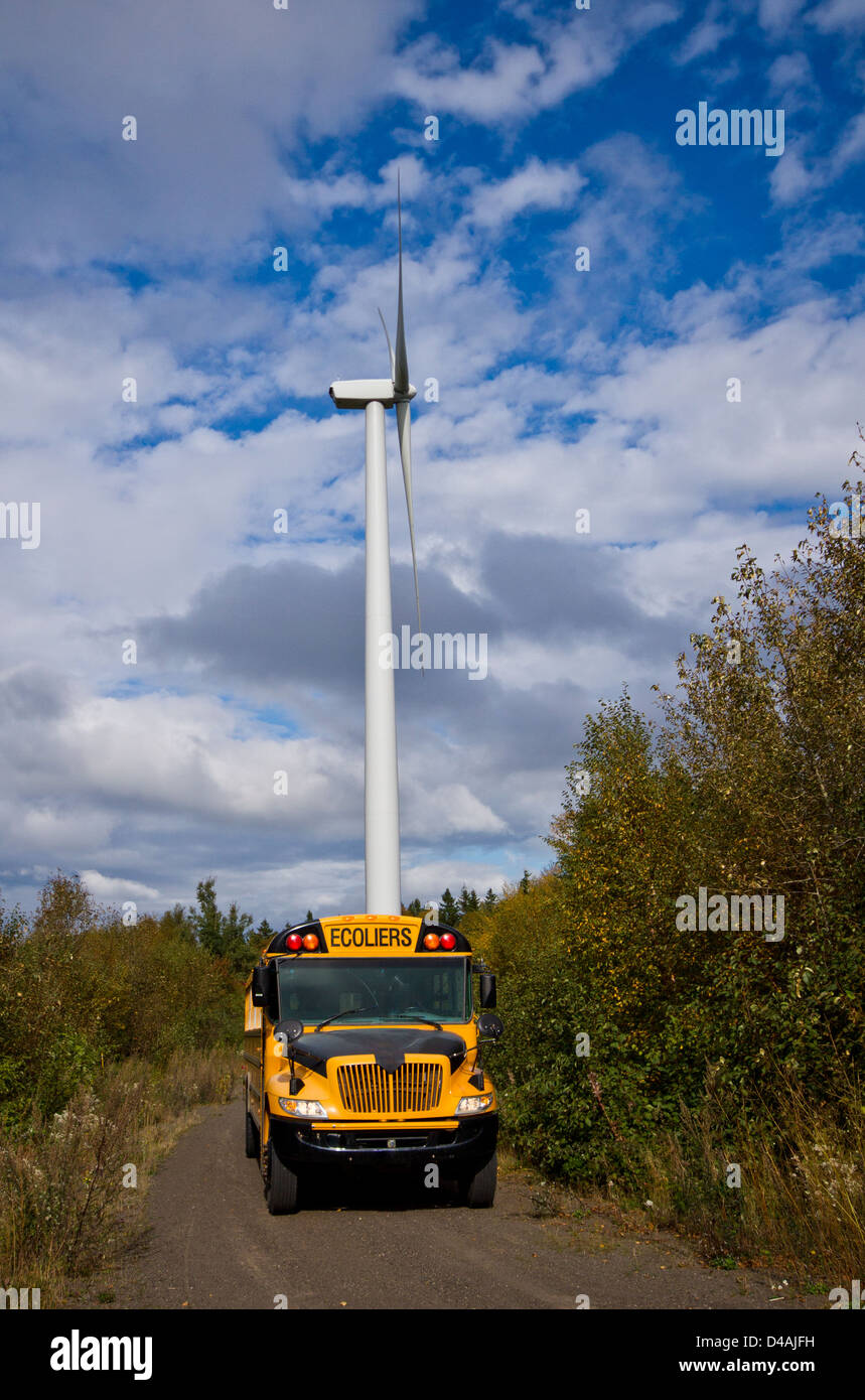 Schulbus vor eine große Windkraftanlage. Stockfoto