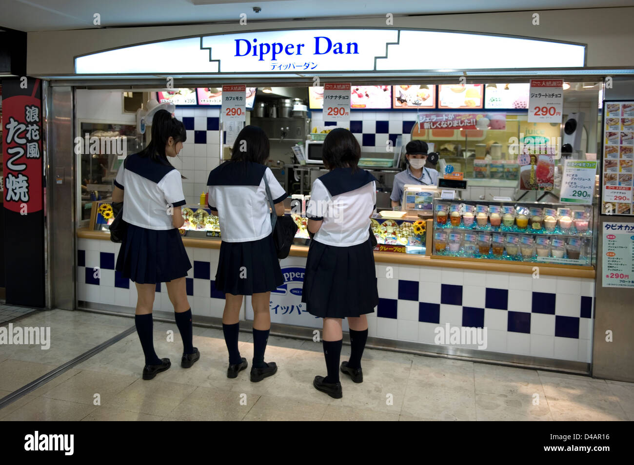 Drei Schulmädchen in Uniform Kauf nach der Schule snack in einer unterirdischen Mall in Nagoya, Japan. Stockfoto