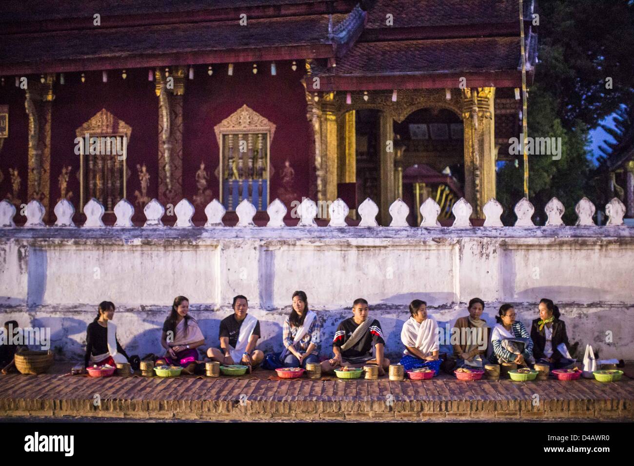 Luang Prabang, Laos. 11. März 2013. Touristen warten in der Dunkelheit für die Tak Bat um vor einem buddhistischen Tempel in Luang Prabang zu starten. Die '' Tak Bat'' ist ein tägliches Ritual in den meisten Laos (und anderen Ländern des Theravada-Buddhismus wie Thailand und Kambodscha). Mönche ihren Tempeln im Morgengrauen verlassen und gehen schweigend durch die Straßen und Menschen setzen Reis und andere Lebensmittel in ihre Almosen-Schalen. Luang Prabang, in Nordlaos, ist vor allem bekannt für den Morgen '' Tak Bat'' wegen der großen Zahl Tempel und Mönche in der Stadt Credit: ZUMA Press, Inc. / Alamy Live News Stockfoto