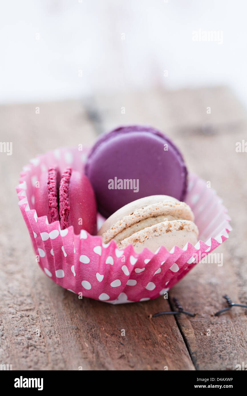 Nahaufnahme von drei verschiedenen aromatisierten Makronen in Papierschale Cupcake auf Holztisch Stockfoto