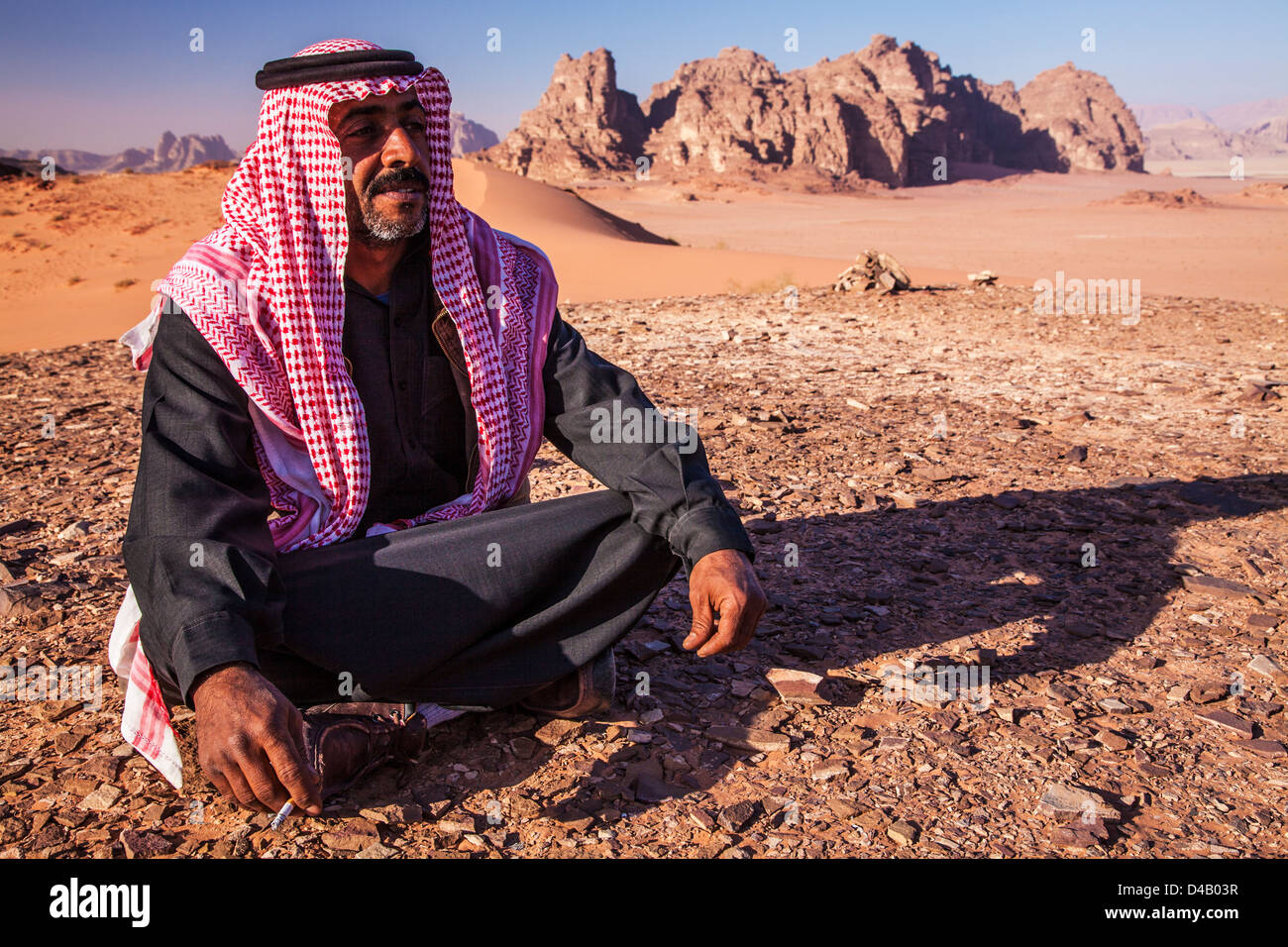 Ein Beduinen-Mann sitzt vor dem Hintergrund der jordanischen Wüste Wadi Rum oder Tal des Mondes Stockfoto