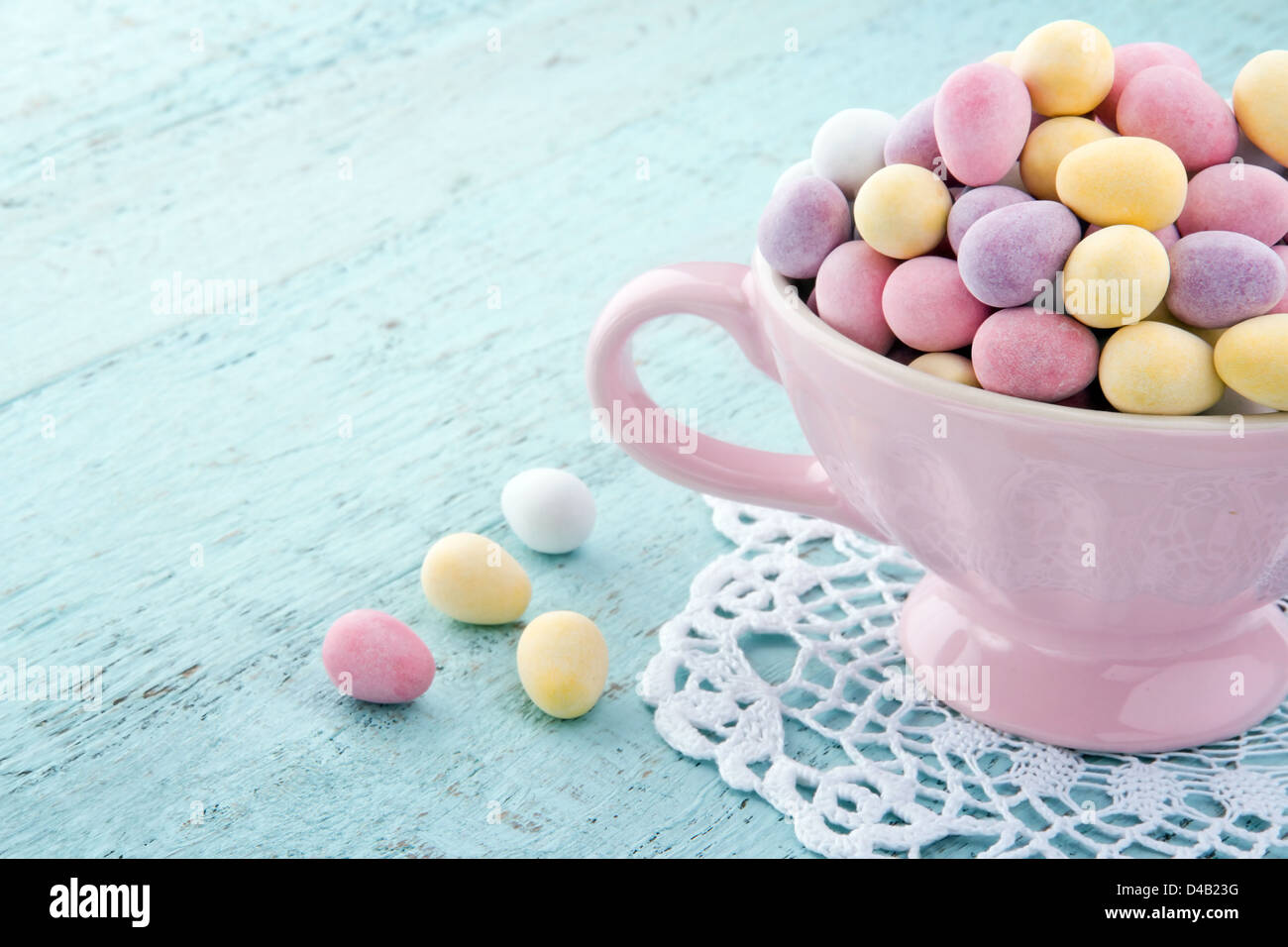 Kleinen Pastellfarben Ostereier in eine rosa Tasse auf Licht blau Holztisch mit Textfreiraum Stockfoto