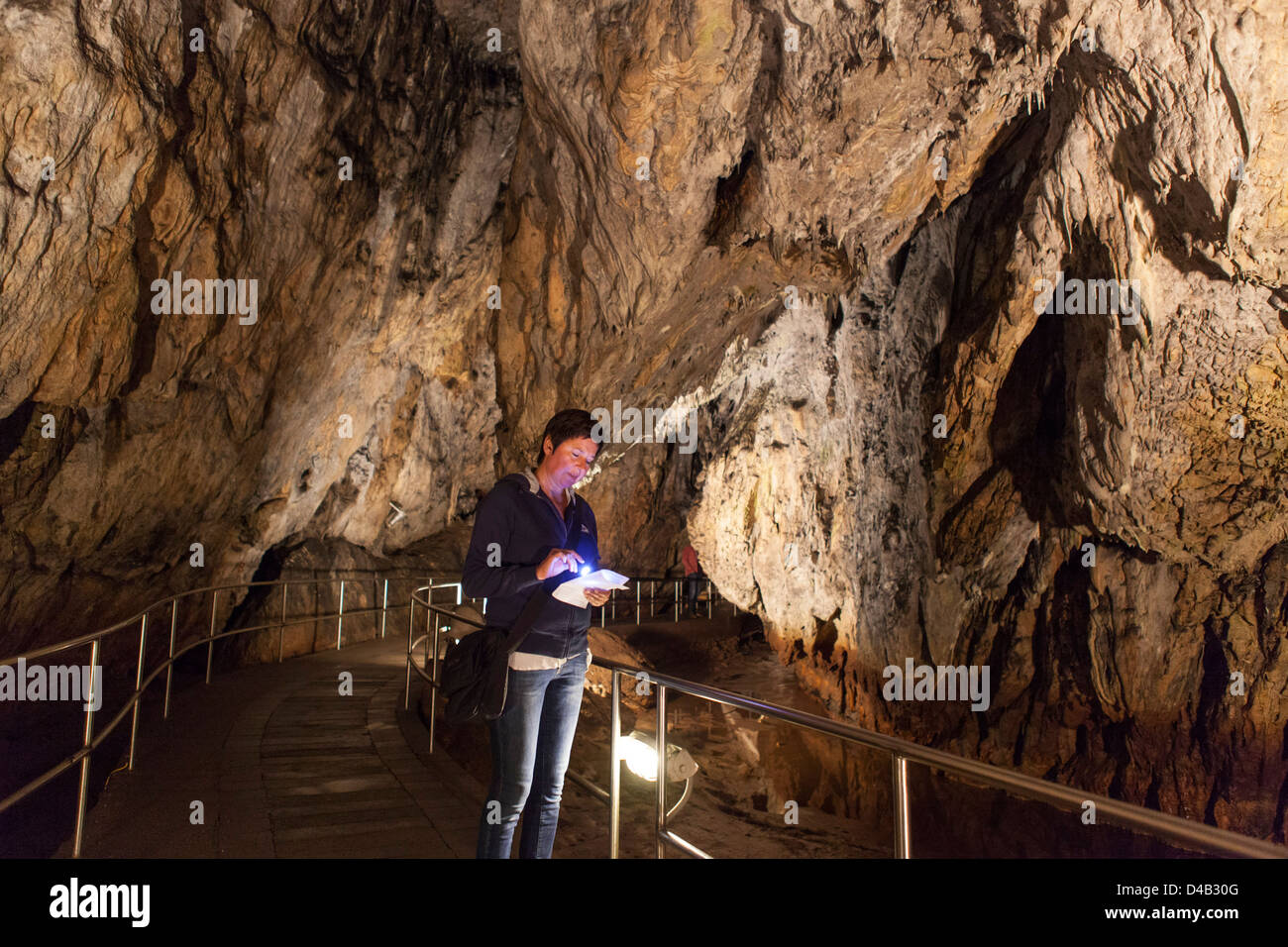 Frau, die gerade Karte mit Fackel in Nationalpark Aggtelek Höhlen in Ungarn, auch genannt Baradla-Domica Höhlen Stockfoto