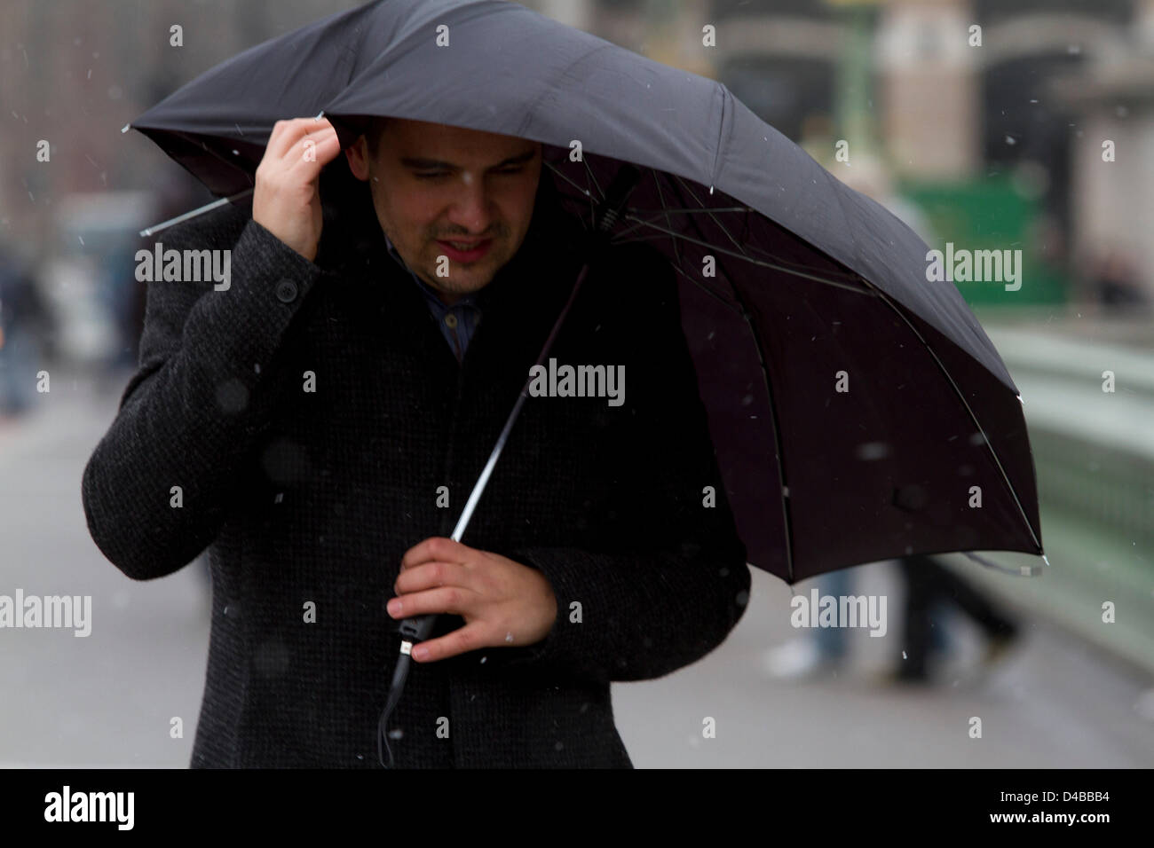 London, UK. 11. März 2013. Ein Mann unter einem Regenschirm vor starkem Wind und Schnee schützt, das Met Office zu rechnen hat Temperaturen dürften zu so niedrig wie-7 C in den nächsten wenigen fallen Tage wie winterliche Bedingungen in vielen Teilen des Vereinigten Königreichs zurückkehren.  Bildnachweis: Amer Ghazzal / Alamy Live News Stockfoto