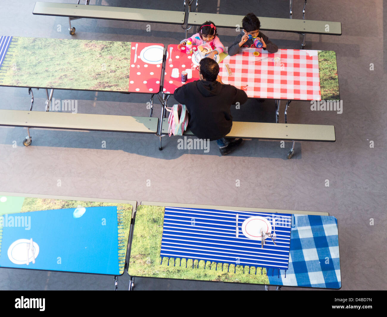 Erhöhte Ansicht der jungen Familie Papa mit Kinder Essen Mittags-Picknick im Cafeteria-Bereich. Stockfoto