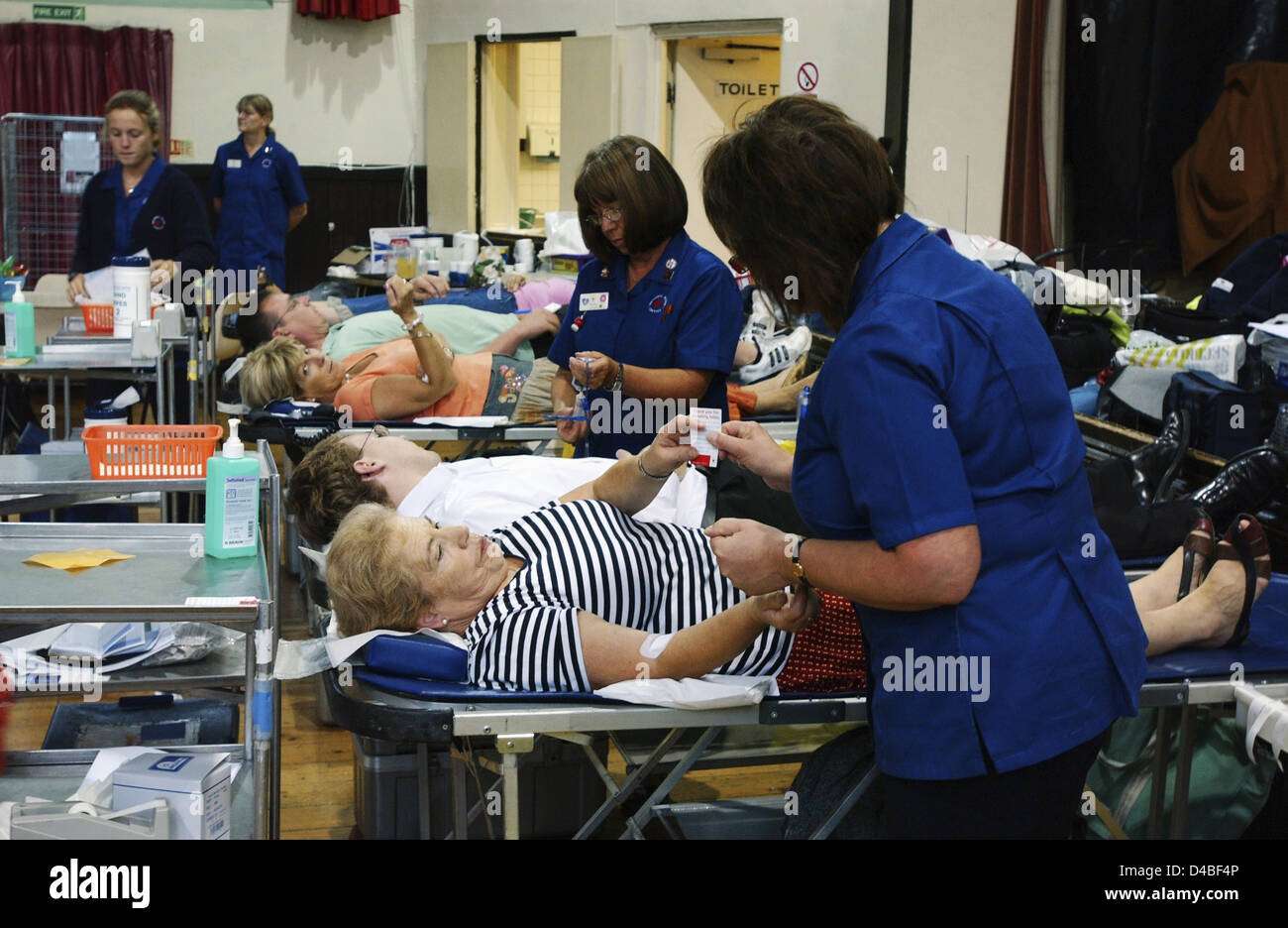 Pflegekräfte kümmern sich während der Sitzung in NHS National Blut Service Sammelstelle Blutspender auf Betten Stockfoto