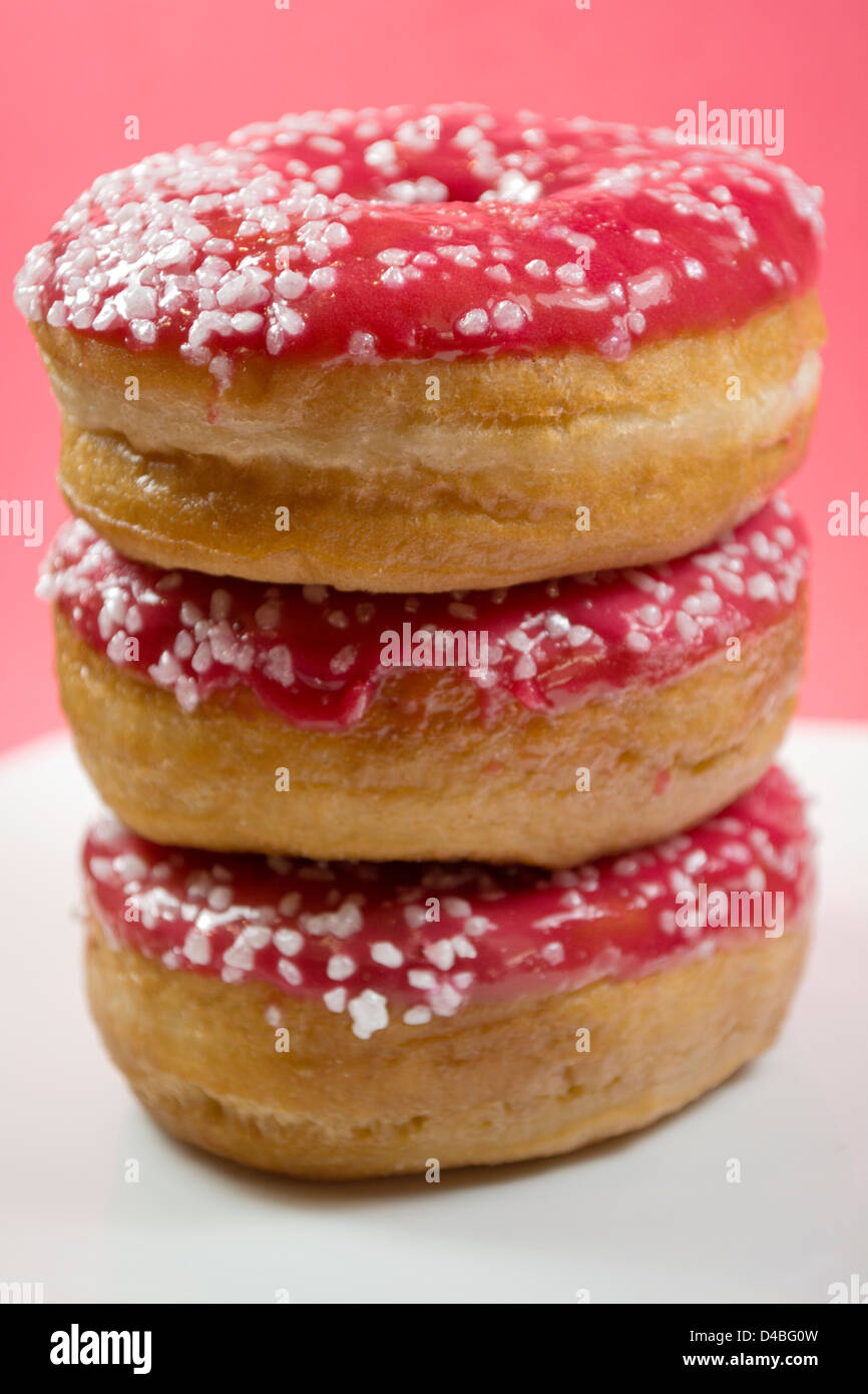 Ein vertikales Bild von drei Krapfen mit rosa Zuckerguss Stockfoto