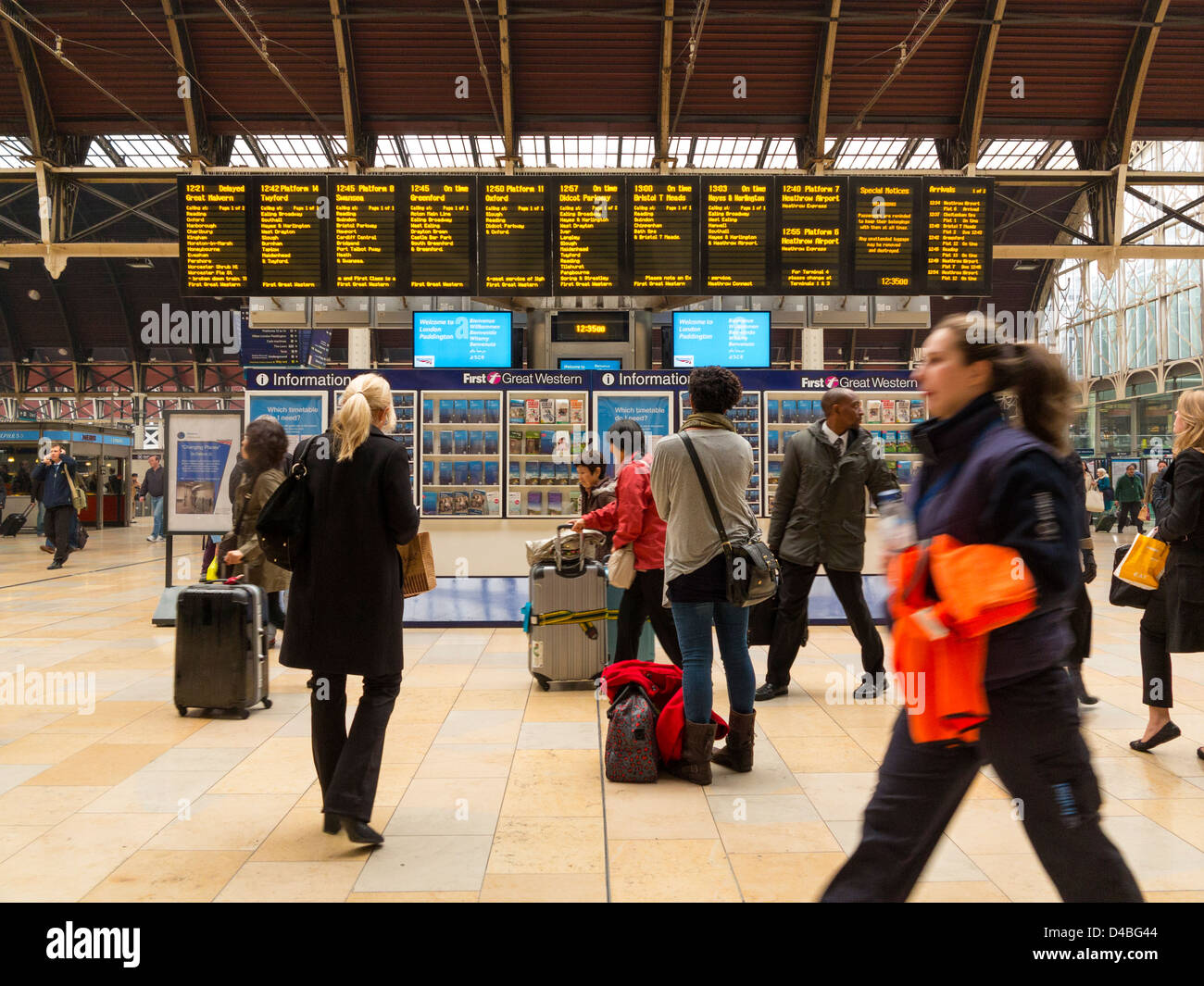 Menschen warten auf Züge und elektronische Schilder am Bahnhof Paddington, London, England Stockfoto