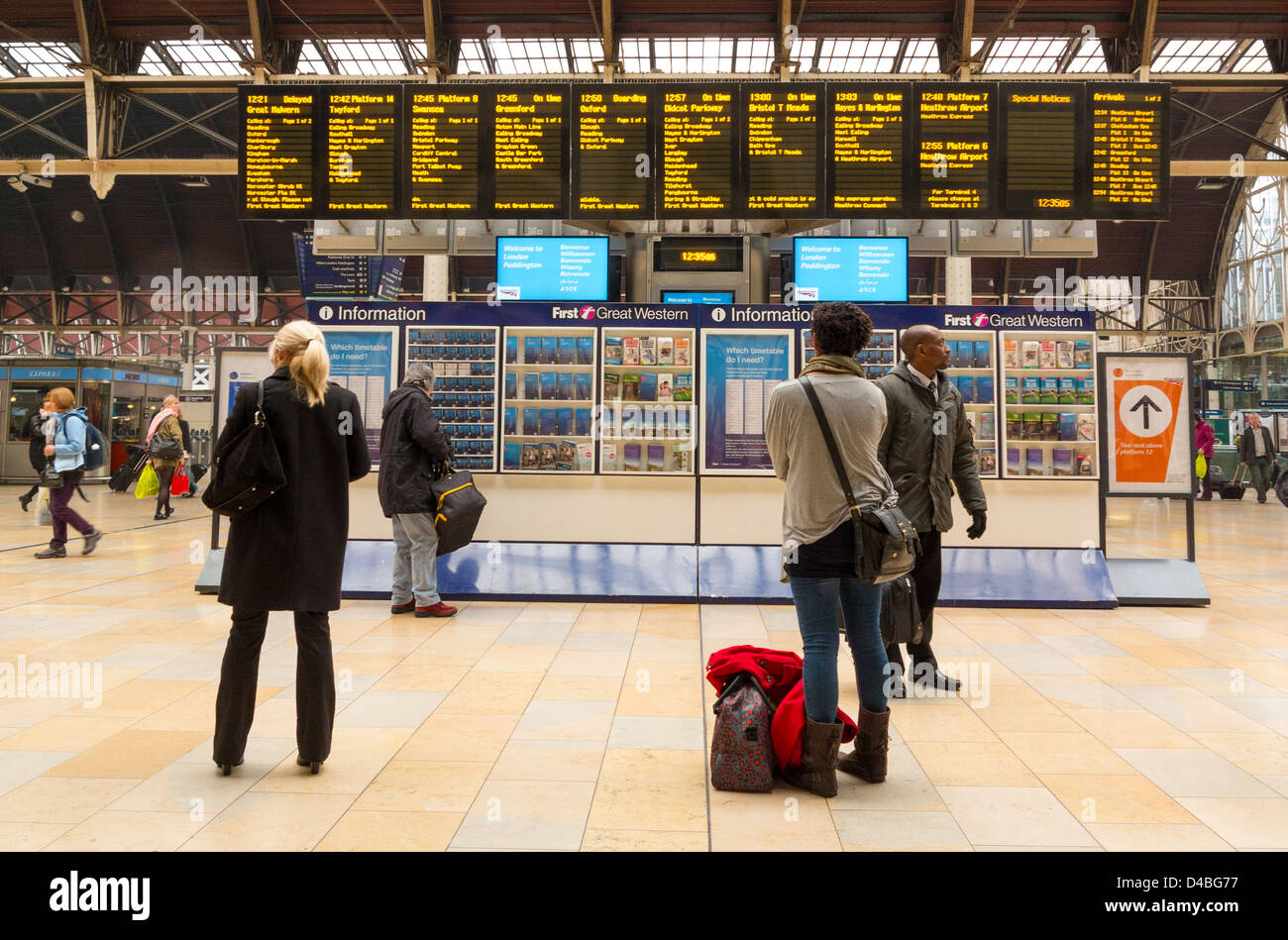 Menschen warten auf Züge und elektronische Schilder am Bahnhof Paddington, London, England Stockfoto