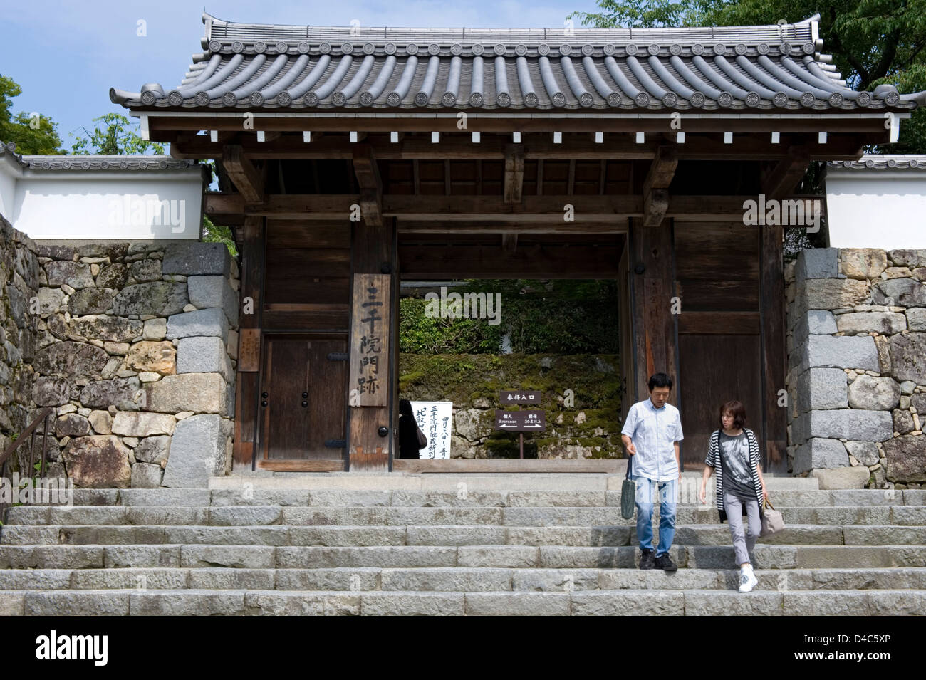 Besucher verlassen durch den Haupteintrag Sanmon Tor der Tendai-Sekte Sanzenin Tempel in ländlichen Dorf von Ohara, Kyoto, Japan. Stockfoto