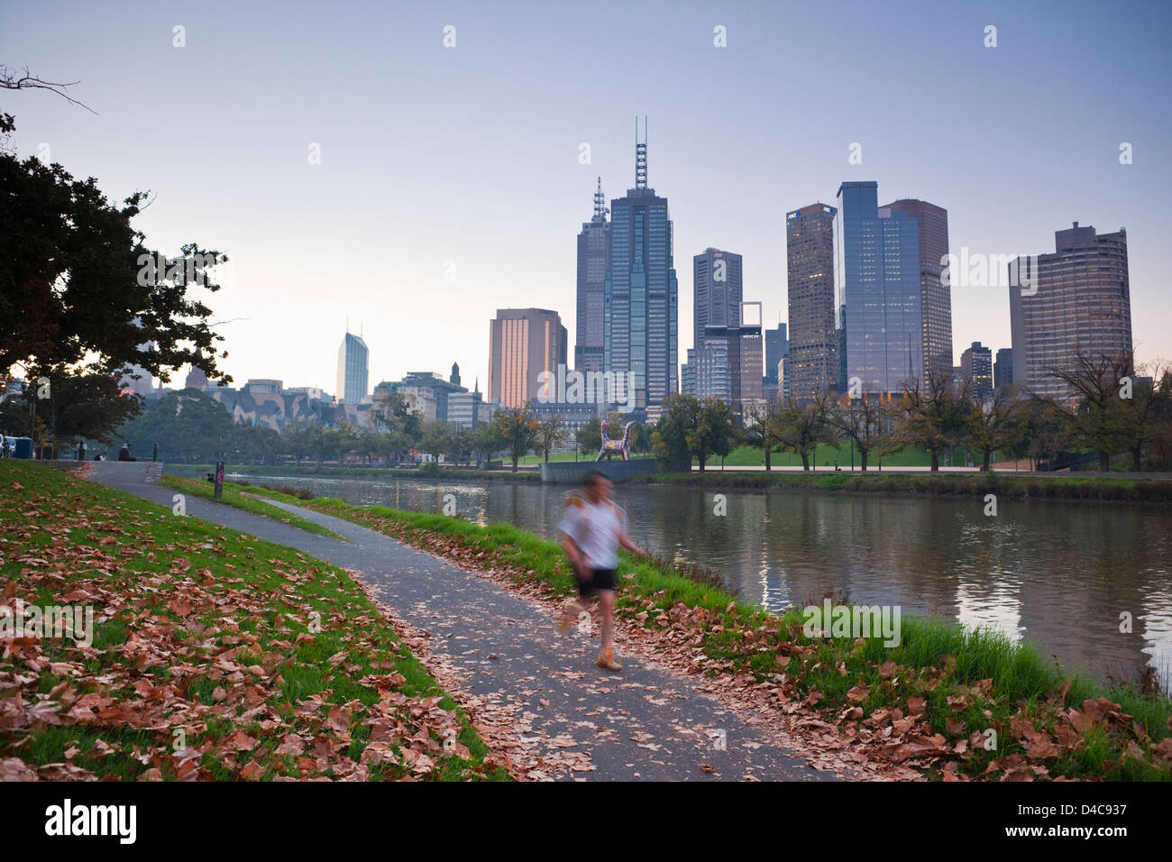 Jogger am Ufer des Yarra River mit Skyline der Stadt im Hintergrund. Melbourne, Victoria, Australien Stockfoto