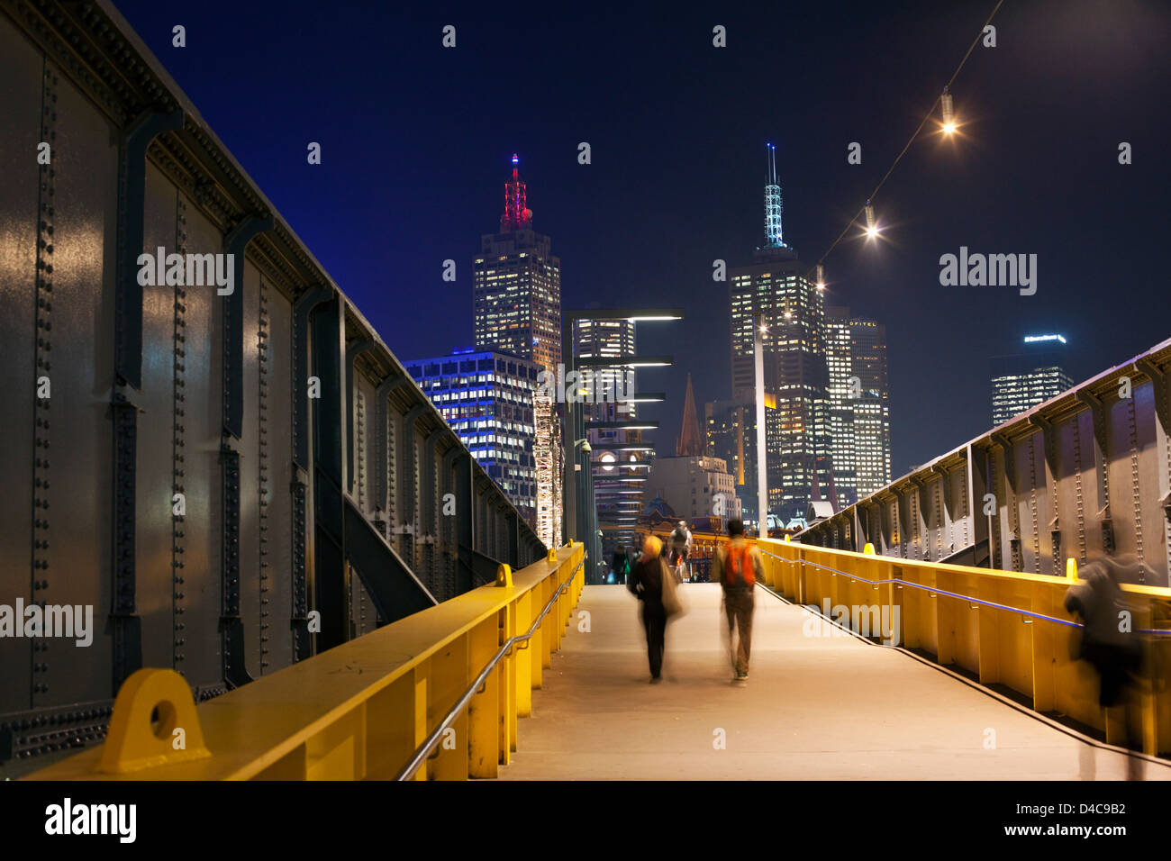 Fußgänger auf Sandridge Bridge bei Nacht mit Skyline der Stadt im Hintergrund. Melbourne, Victoria, Australien Stockfoto