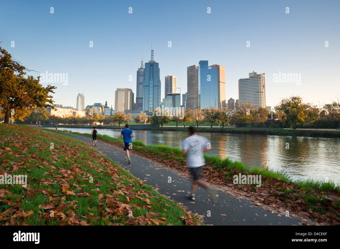 Jogger am Ufer des Yarra River mit Skyline der Stadt im Hintergrund. Melbourne, Victoria, Australien Stockfoto