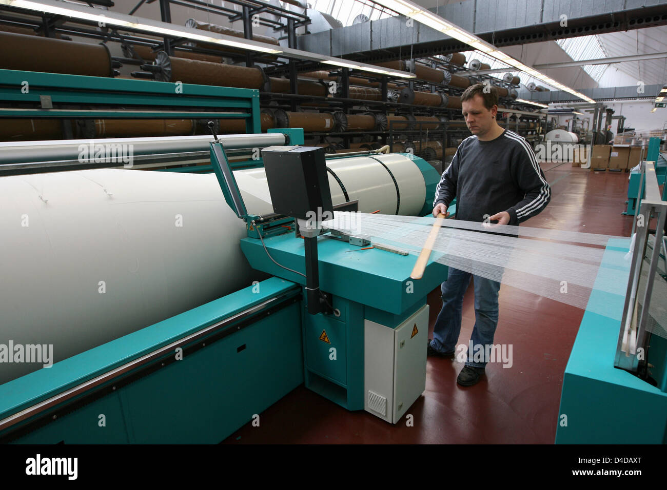 Bernhard Olberding, Mitarbeiter der Vorhang Hersteller ADO, betreibt eine Maschine im Werk des Unternehmens in Papaenburg, Deutschland, 3. April 2008. Das traditionsreiche Unternehmen ist ein führender Hersteller von Gardinen und Tapisserie, bekannt für seine so genannten goldenen Webkante. Foto: Friso Gentsch Stockfoto