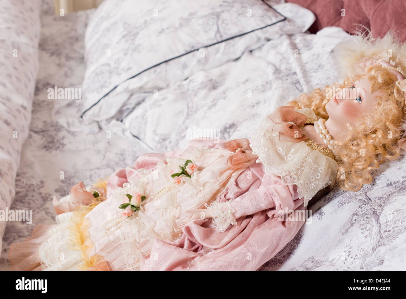 Schöne Vintage Puppe mit dem lockigen blonden Haar in locken und gekleidet im Stil des 19. Jahrhunderts auf einem Kissen liegend Stockfoto
