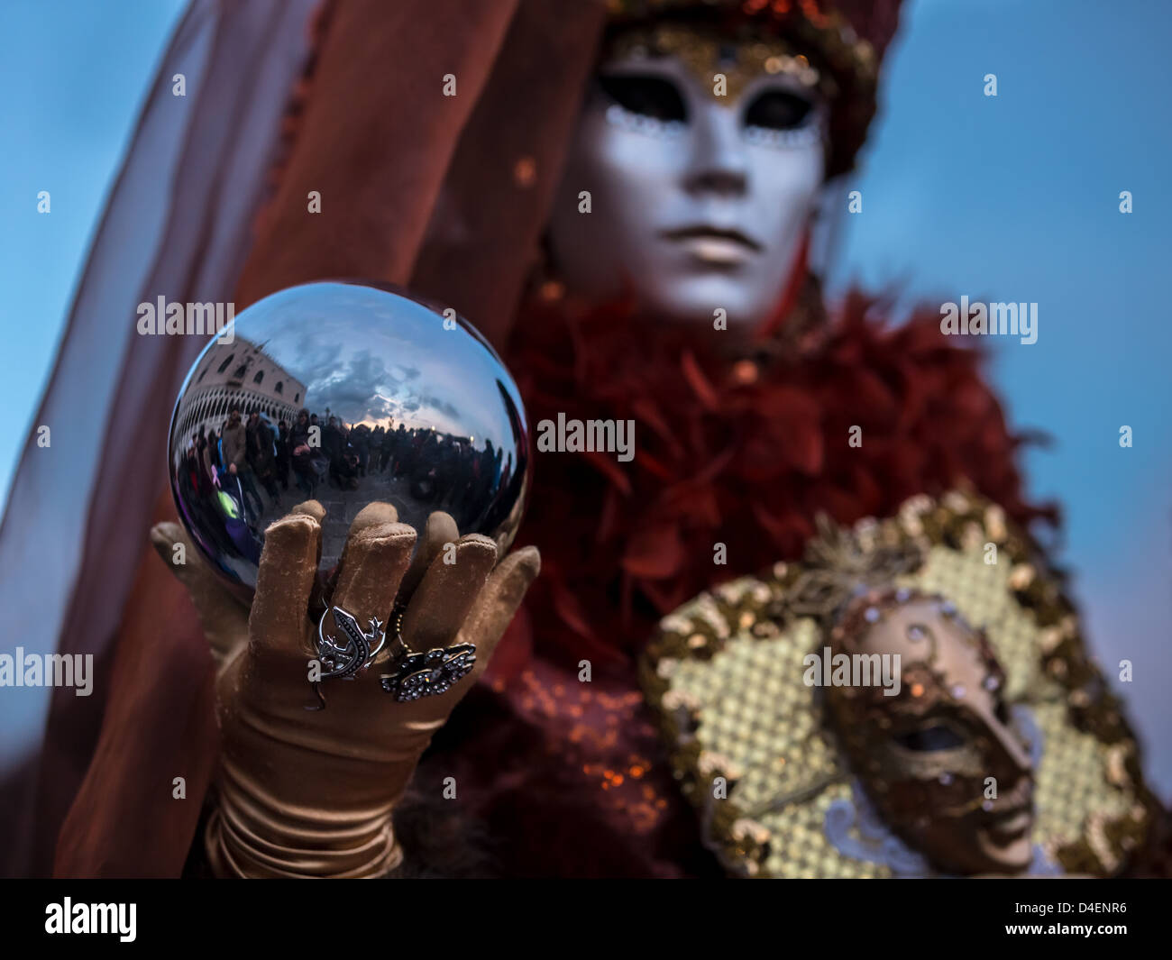 Eine Frau gekleidet für den Karneval in Venedig hält eine Metallkugel, in der St-Marco und Menschen reflektiert werden, Venetien, Italien Stockfoto