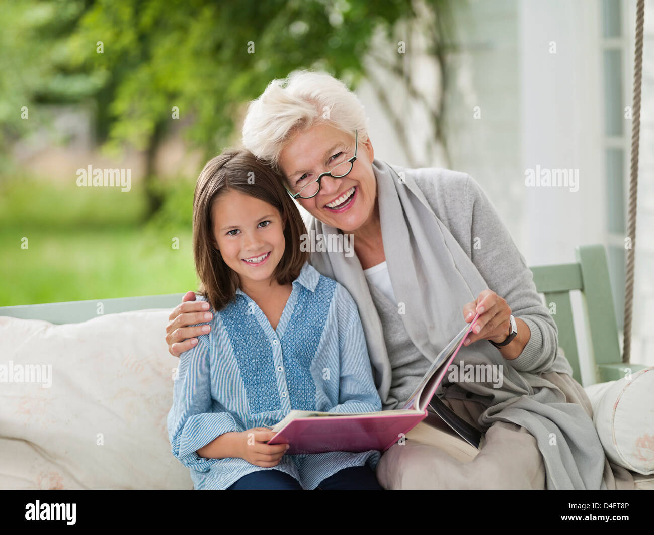 Frau und Enkelin lächelnd in Veranda-Schaukel Stockfoto
