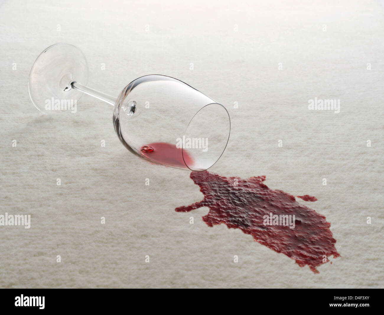 Glas Rotwein auf dem weißen Teppich verschüttet Stockfoto