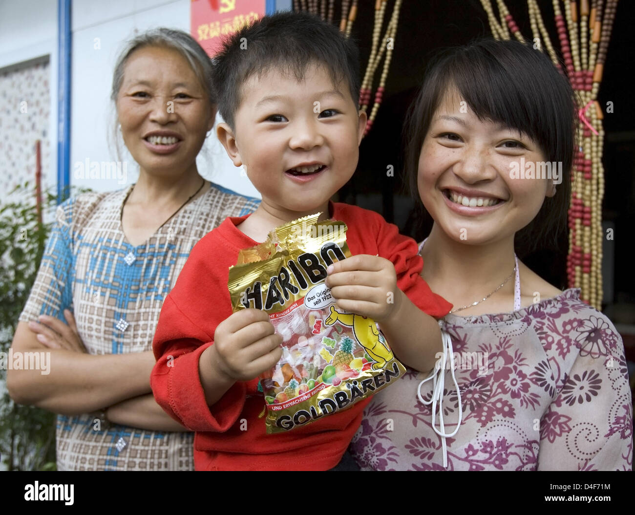 Eine Mutter und ihr Kind freuen sich auf einen Beutel mit Gummibärchen, die ihnen während des Besuchs von Bundesaußenminister Frank-Walter Steinmeier bei einem Container Gehäuse Fläche in Dujianyan, China, 15. Juni 2008 gegeben. Dujiangyan in der chinesischen Provinz Sichuan ist einer der drei Gemeinden von der administrativen Bezirk Chengdu, die am 12. Mai 2008 von dem Erdbeben betroffen war. 80 pe Stockfoto