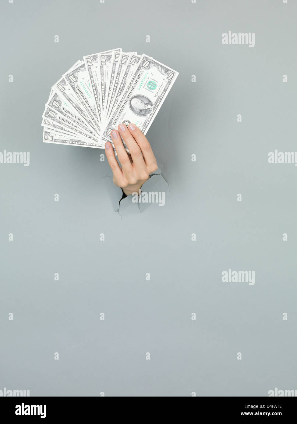 Nahaufnahme des weiblichen Hand mit Geld durch ein zerrissenes Papier grau Stockfoto