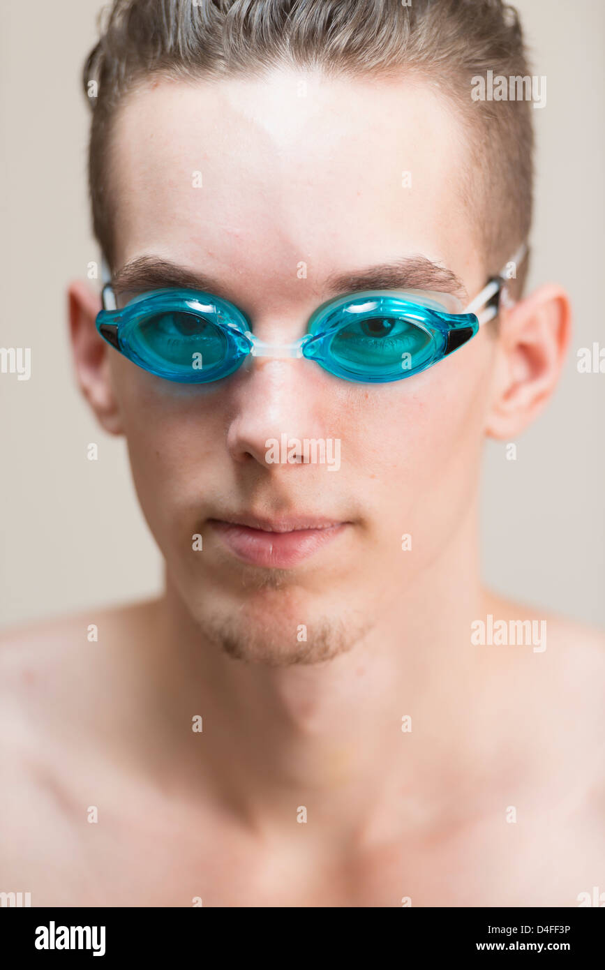 Junge sportliche männliche Smimmer schauen zuversichtlich und tragen blaue Swimming goggles Stockfoto