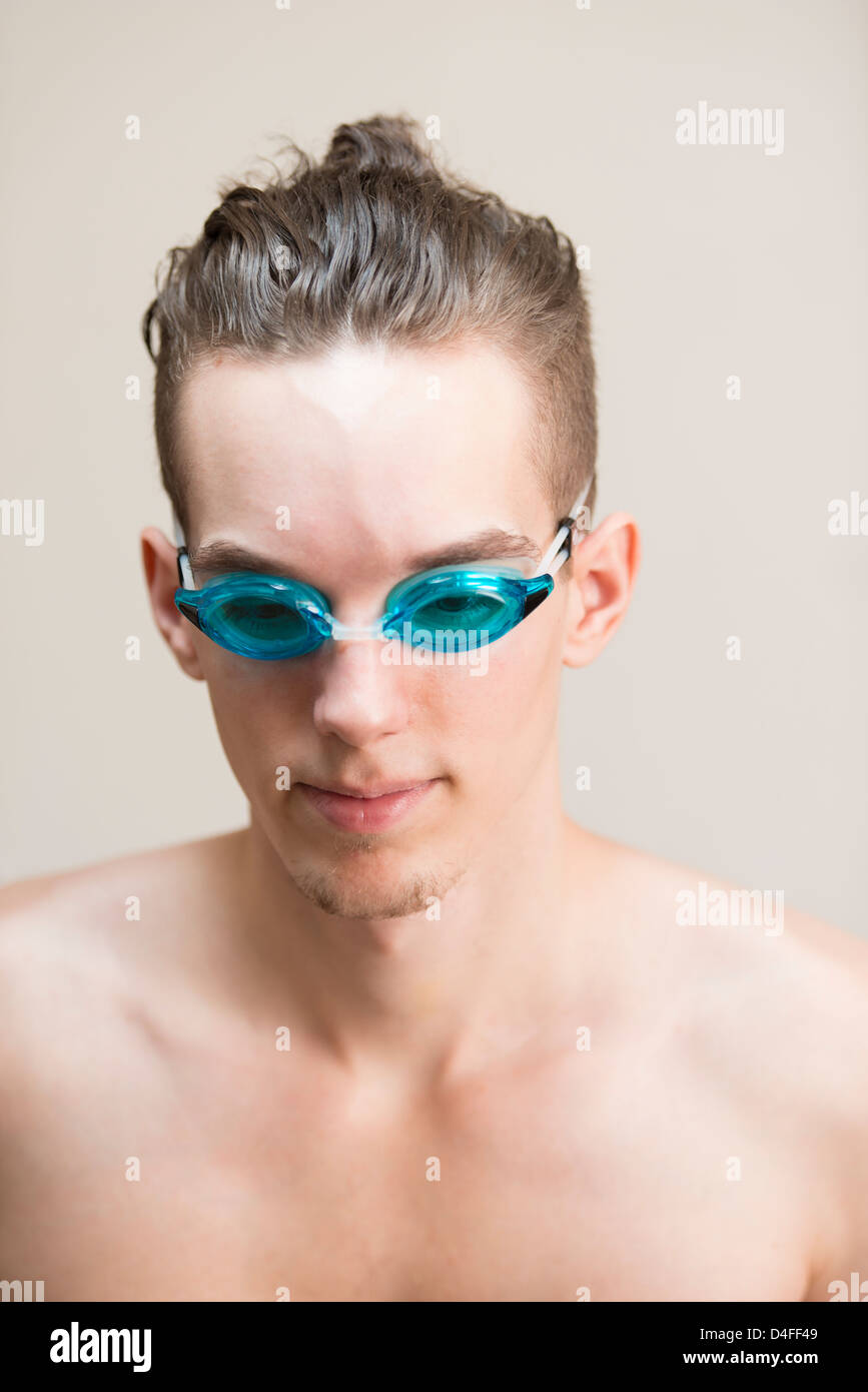 Junge sportliche männliche Smimmer schauen zuversichtlich und tragen blaue Swimming goggles Stockfoto