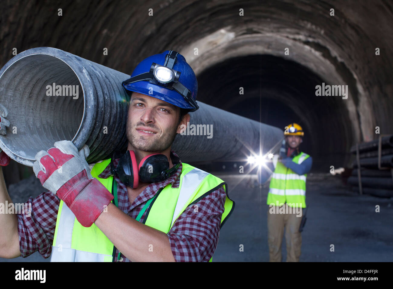 Arbeiter tragen langes Rohr im tunnel Stockfoto