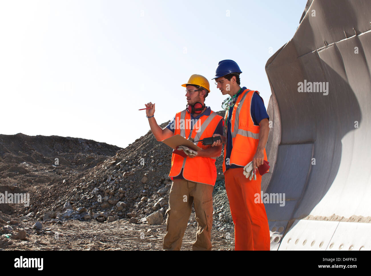 Arbeitnehmer, die reden von Maschinen im Steinbruch Stockfoto