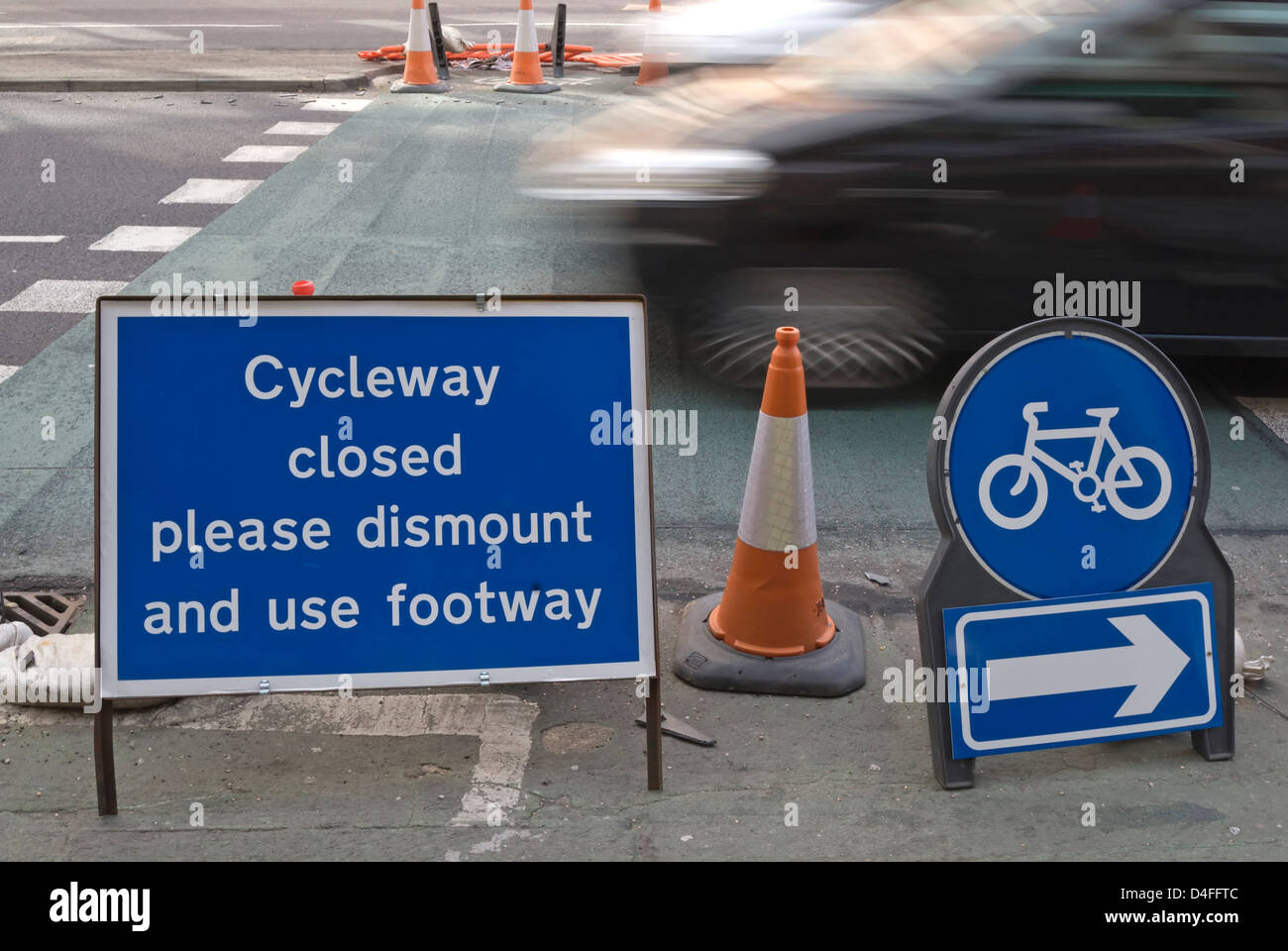 Cycleway geschlossen bitte demontieren und Fußweg Zeichen mit vorbeifahrenden Bewegungsunschärfe Auto, Kingston nach Themse, Surrey, england Stockfoto