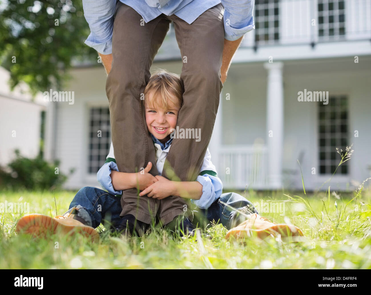Junge spähen aus zwischen Vaters Beinen Stockfoto