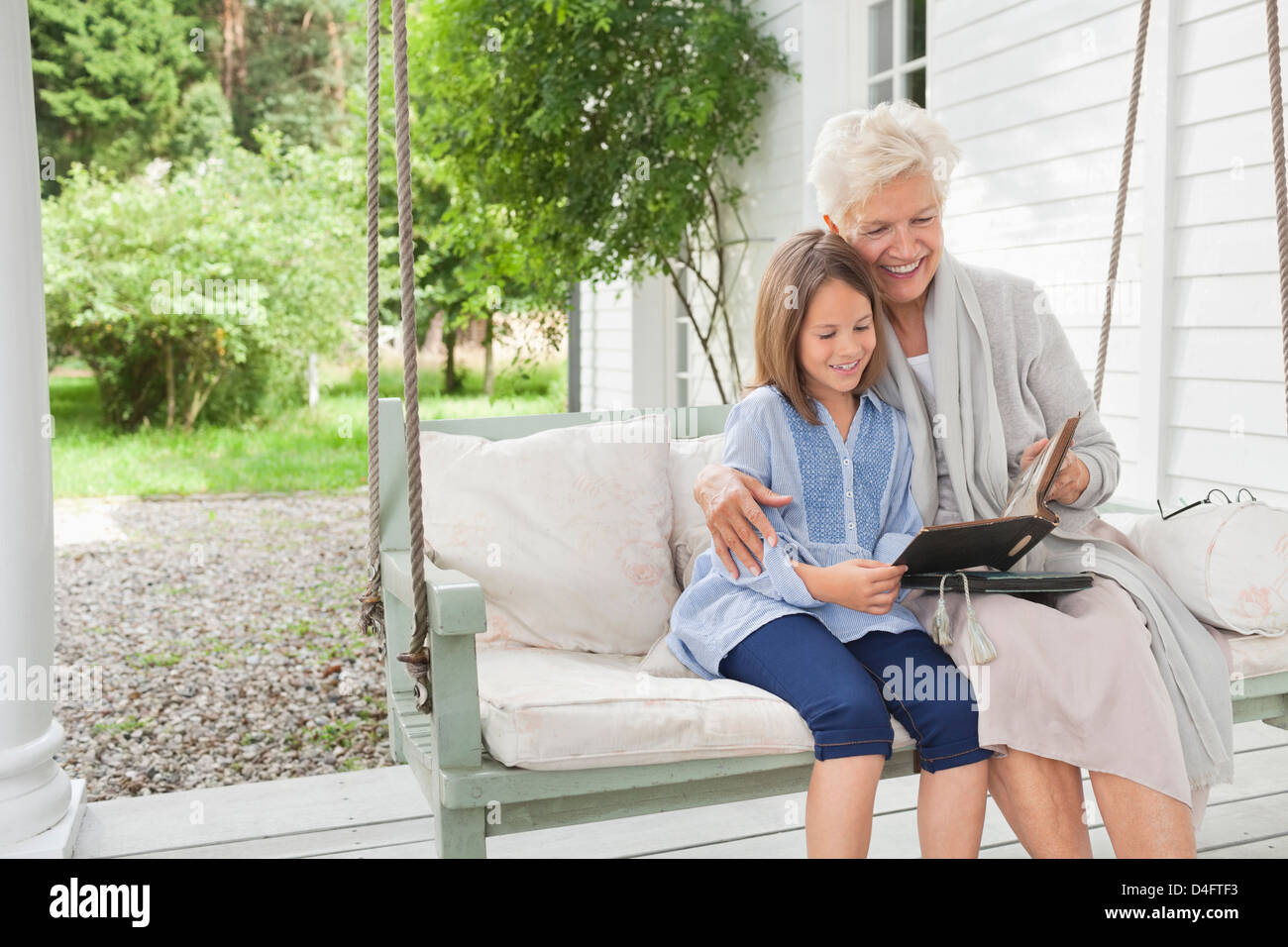 Frau und Enkelin lesen auf Veranda-Schaukel Stockfoto
