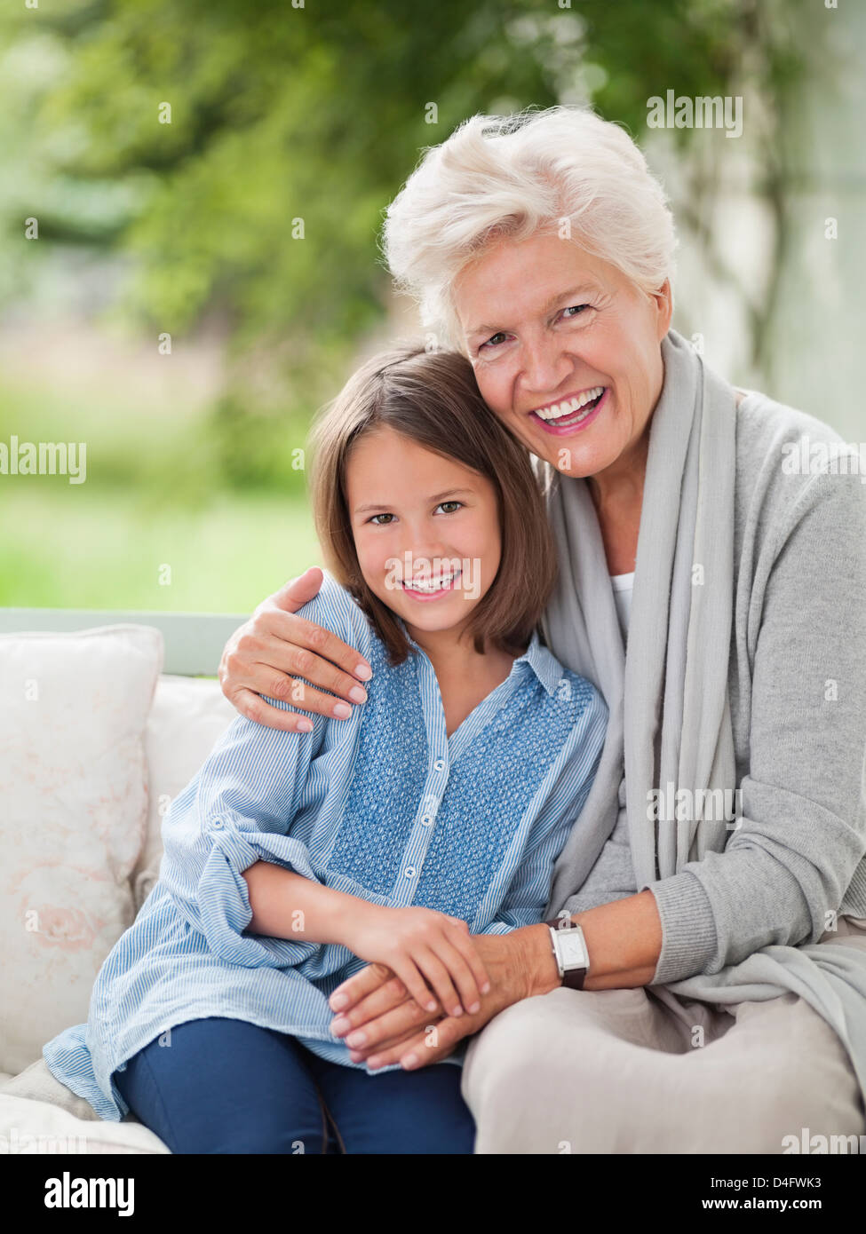 Frau und Enkelin lächelnd auf Veranda-Schaukel Stockfoto