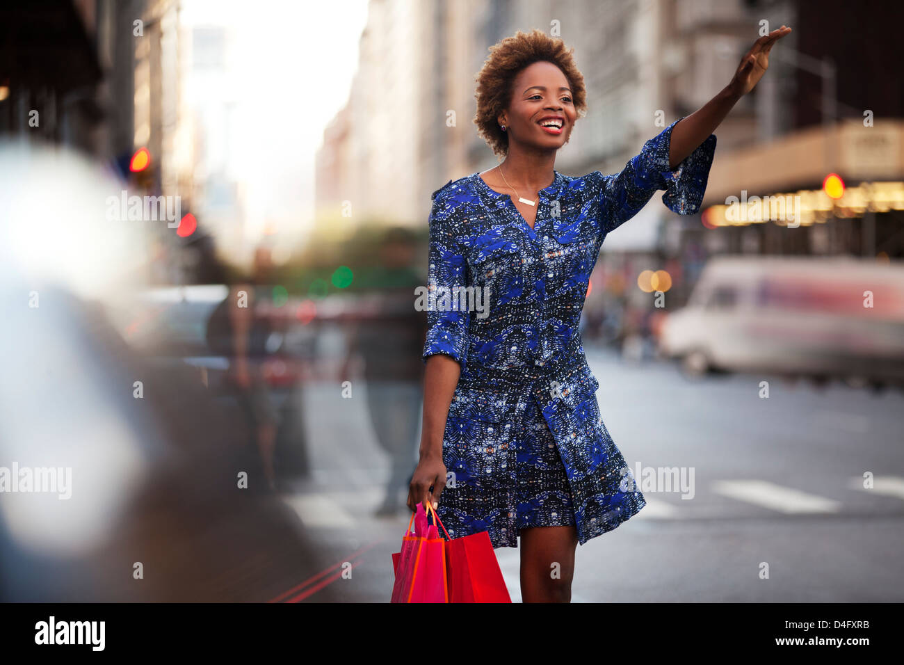 Frau mit shopping Taschen hagelt Taxi auf Stadtstraße Stockfoto