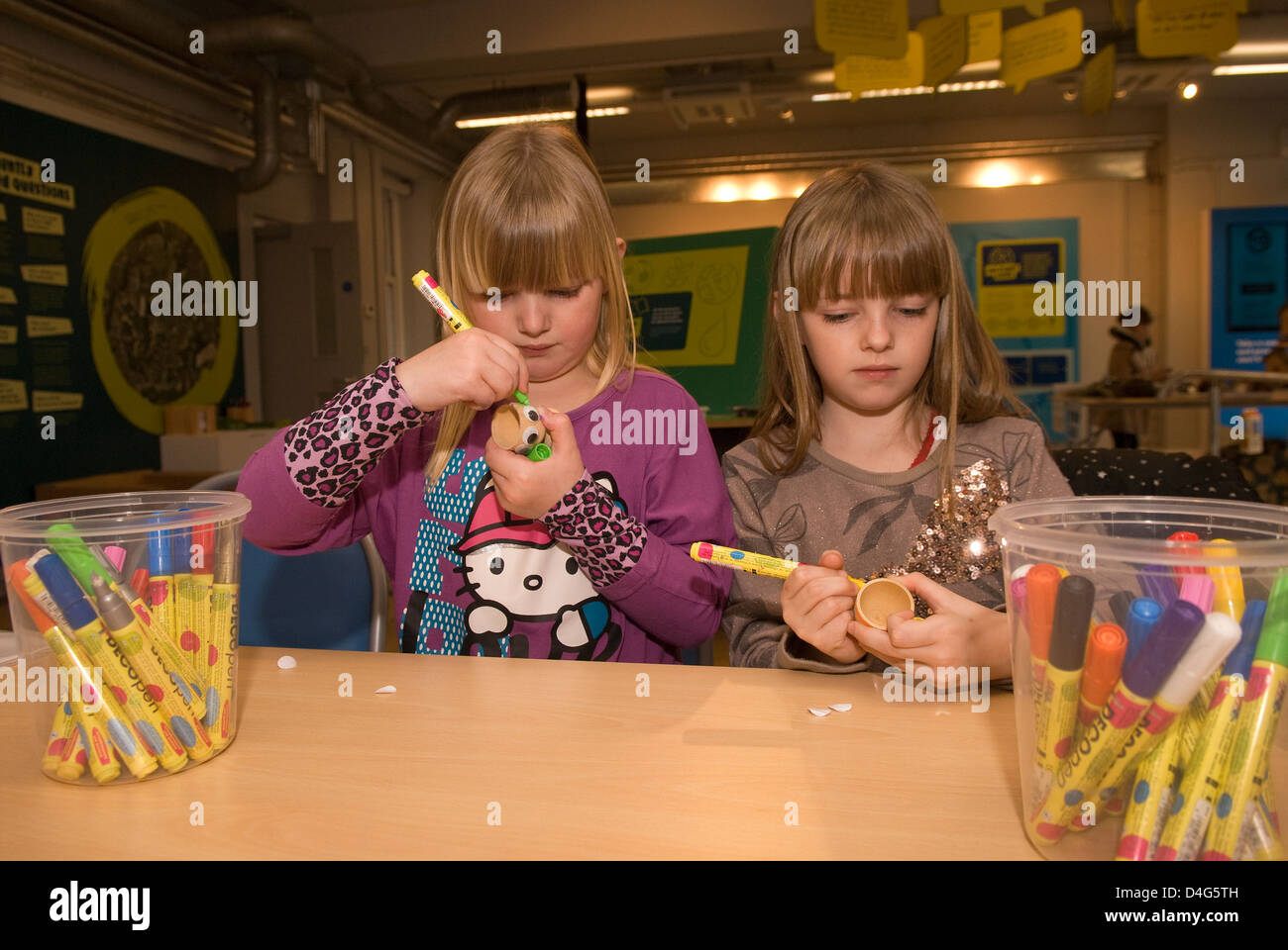 Zwei Schwestern, 6 & 7 Jahre alt, Malerei Eierbecher an einem eco station Tag der offenen Tür mit Hühnern, Bordon, Hampshire, UK. Stockfoto