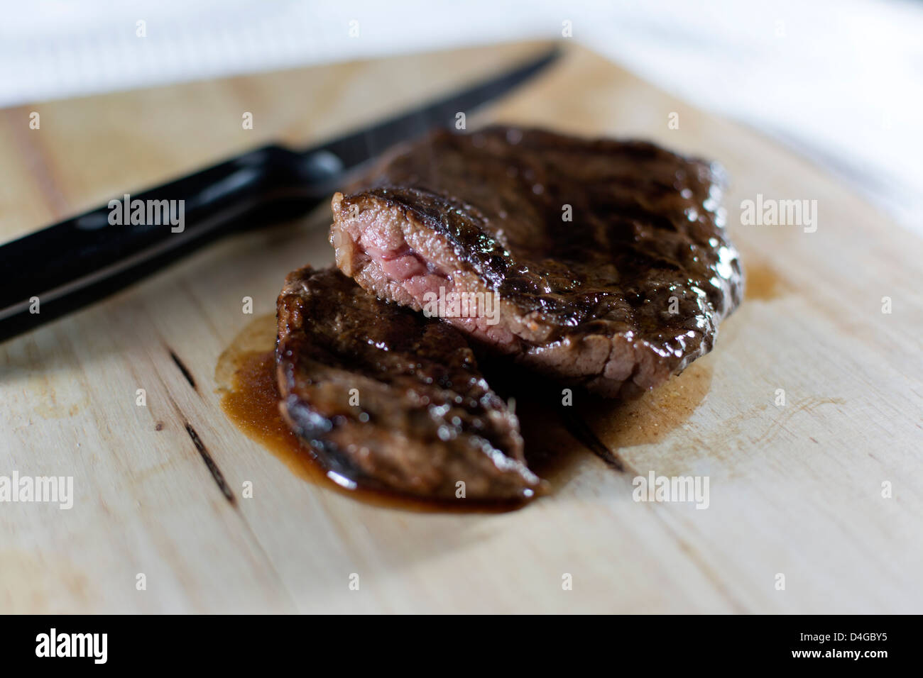 Selten ein Medium Steak, halbieren, mit einem Steak-Messer an der Seite auf einem Holzbrett gegart Stockfoto